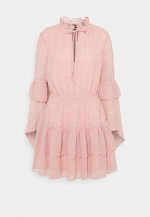 Robe rose clair avec un col à volants et des manches longues. Fabriquée en tissu texturé à motif à pois, elle présente une jupe à volants et un cordon de serrage.