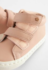 Lyserøde læder højtopsneakers med to velcro-stropper, hvid sål og en lille gul stjerne accent på den øverste sektion.