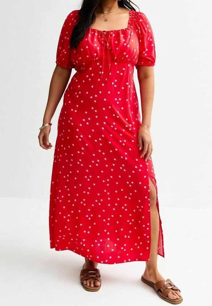 Abito maxi rosso a pois con maniche a palloncino, scollatura quadrata e spacco laterale. Realizzato in tessuto leggero. Abbinato a sandali piatti marroni.