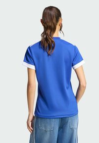 Blå sportst-shirt med vita detaljer på ärmar och krage. Tillverkad i lättviktstyg och har en avslappnad passform.