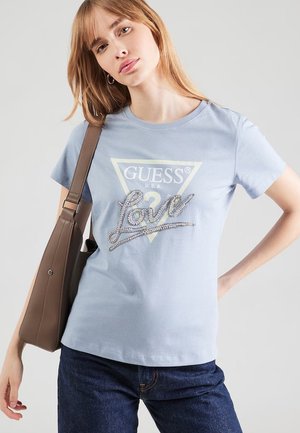 Lichtblauw T-shirt met korte mouwen, met een witte driehoek met de tekst "GUESS USA" en een zilveren paillettenversiering met het woord "love" aan de voorkant.