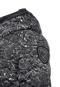 Gewatteerd donsjack in zwart-wit met een bloemenpatroon, geribbelde manchetten en een zwart embleem met strass-steentjes op de schouder.