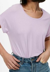 T-shirt violet clair à manches courtes avec un col rond, en tissu doux, associé à un jean en denim bleu taille haute.