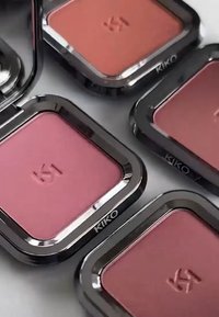 Cuatro estuches cuadrados de colorete con bordes negros brillantes, que presentan tonos de rosa y coral. Cada uno tiene "K1" y "KIKO" grabados en la superficie.