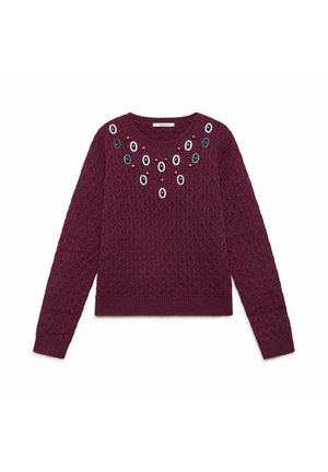 Pull bordeaux avec un motif en maille texturée, col rond, et ornements décoratifs en ovale noir, blanc et rouge près du col.