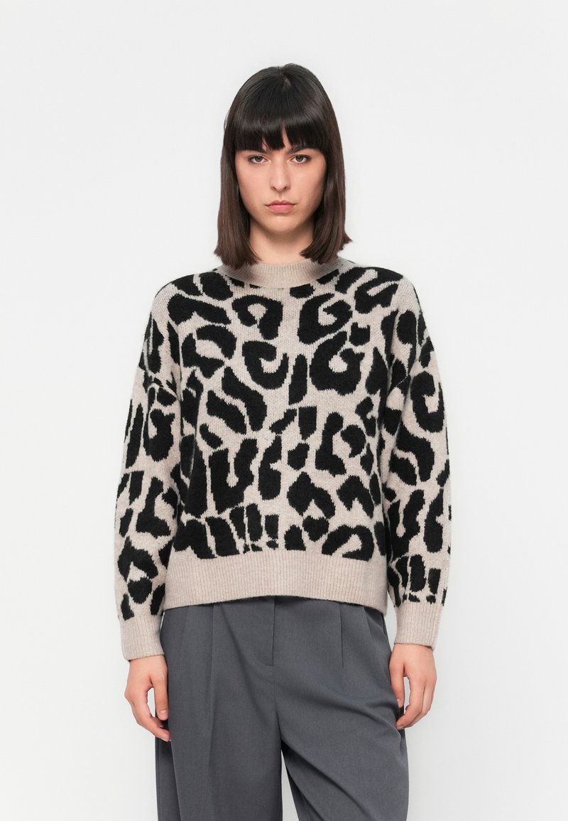Maglione beige chiaro con grande stampa animale nera, scollo rotondo e maniche lunghe. Tessuto lavorato a maglia con vestibilità morbida.
