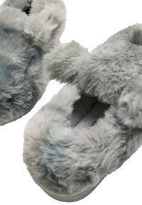 Zapatillas grises y peludas con un exterior suave y acolchado, forma redondeada, diseño abierto y suela de color claro, adecuadas para uso en interiores.