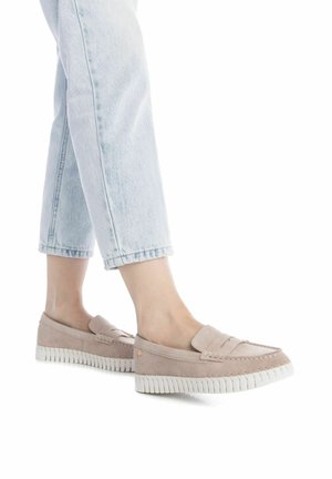 Mocasines de ante rosa claro con una suela blanca estriada, que presentan una costura elevada y una tira decorativa en la parte frontal. Combinados con jeans azul claro.