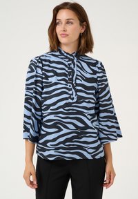 Blusa a righe blu e nere con colletto arricciato, maniche a tre quarti e dettagli con bottoni sul davanti. Tessuto a trama piatta.