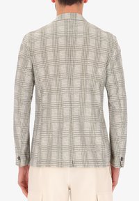 Blazer grigio chiaro con un motivo a quadri in grigio scuro. Presenta una vestibilità su misura, polsini con un bottone singolo e revers a punta. Tessuto testurizzato.