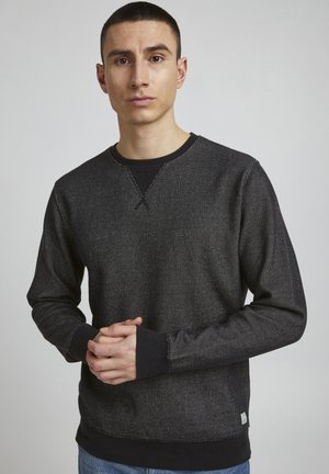 Zwarte sweatshirt van textuurstof, met een contrasterende kraag en manchet. Heeft een ronde hals, lange mouwen en een klein merklabel aan de onderkant.