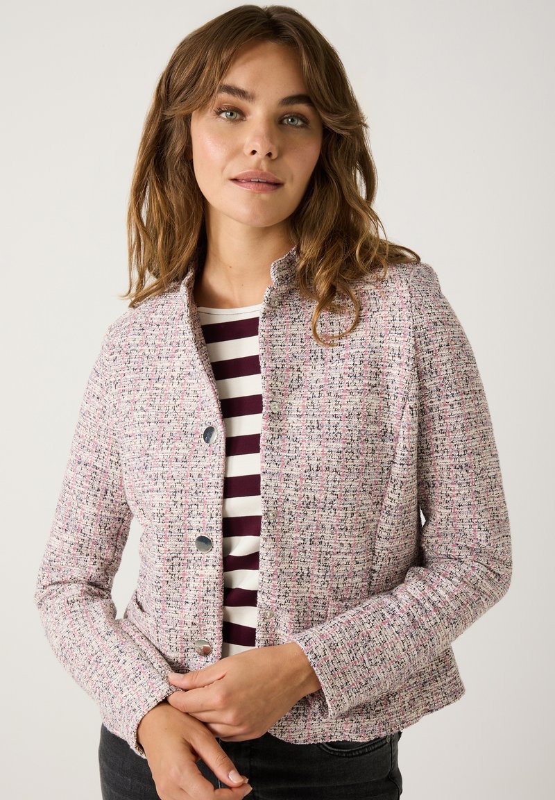 Heller rosa strukturierter Blazer mit dezentem Muster. Verfügt über silberne Knöpfe, einen Stehkragen und eine taillierte Silhouette. Kombiniert mit einem gestreiften Oberteil.