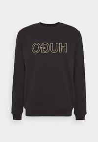 Zwart sweatshirt met lange mouwen, voorzien van een grote, omgekeerde crème-kleurige tekst "HUGO" aan de voorkant. Gemaakt van zacht materiaal met een ronde hals.