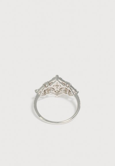 Bague en argent vue par en dessous montrant un sertissage en treillis géométrique conçu pour contenir plusieurs pierres.