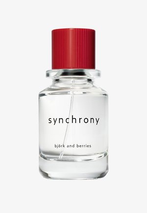 Clear glass perfume bottle with red cap labeled "synchrony" and "björk and berries" showing liquid and spray tube inside.