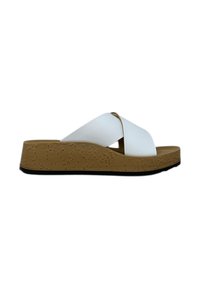 Sandal con cinturini incrociati bianchi su una suola piatta marrone texturizzata, caratterizzato da un design slanciato e una finitura in materiale morbido.