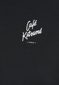 Fekete anyag, fehér hímezett szöveggel "Café Kitsuné" és "PARIS", sima textúrával és testhez simuló kialakítással.