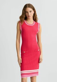 Rotes geripptes Strickkleid mit kurzen Ärmeln, versehen mit weißen Streifenakzenten am Halsausschnitt und Saum sowie zwei Fronttaschen mit Knopfdetails.