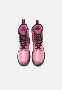 Ροζ παπούτσια μπότες από δερμάτινη λουστρίνι με μαύρα κορδόνια και μαύρη εξωτερική σόλα. Διαθέτουν επενδεδυμένο γιακά και κίτρινη ετικέτα με το λογότυπο για εύκολο τράβηγμα.