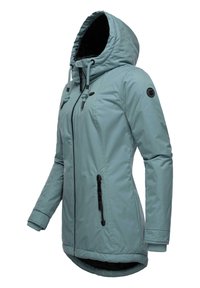 Šviesiai mėlynas parka tipo švarkas su pritaikytu kapišonu, priekyje užtrauktukas, dvi šoninės kišenės su užtrauktuku ir juodos spalvos akcentai. Yra grioveliai ant rankovių ir ilgesnė nugaros dalis.