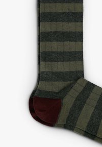 Calcetines a rayas en verde oscuro y gris, con un diseño acanalado y un acento burdeos en el talón. Fabricados con tejido texturizado.