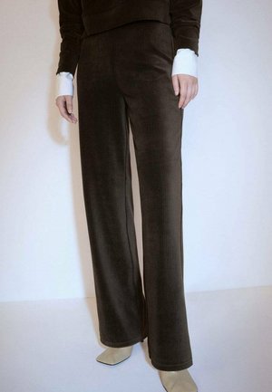 I pantaloni a zampa d'elefante in corduroy marrone presentano una texture morbida e sottili righe verticali, abbinati a un orlo bianco a contrasto.
