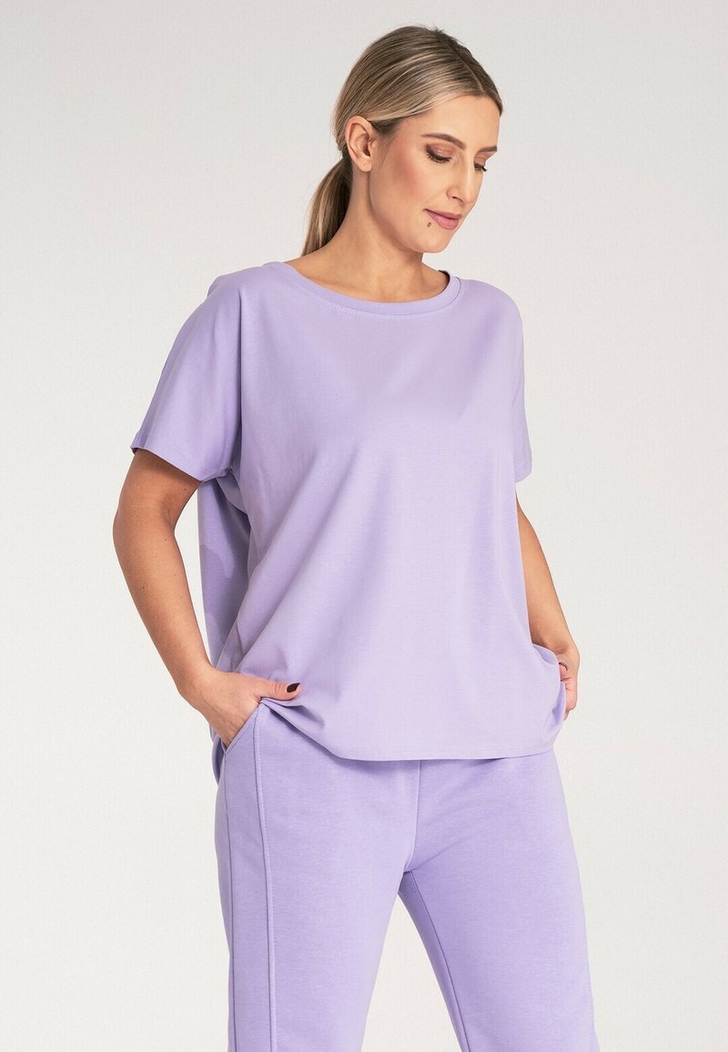 Fioletowy zestaw odzieży domowej, w skład którego wchodzi luźna bluzka z krótkim rękawem i okrągłym dekoltem, o swobodnym kroju, połączona z dopasowanymi, miękkimi, zwężającymi się spodniami.
