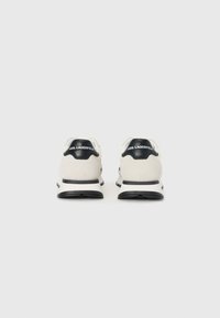 Lagerfeld sneakers med hvit overdel med svarte detaljer, rund form og teksturert materiale. Logo på hælen og en solid svart såle.