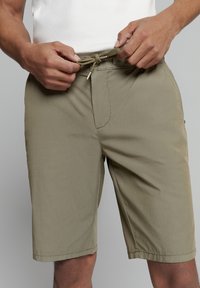 Khaki shorts van lichtgewicht stof met een elastische taille en trekkoord. Kenmerken een gladde textuur en een voorzak.