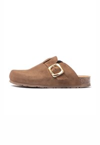 Sabot en daim marron avec un bout rond, une sangle ajustable et un détail en boucle dorée. Présente une semelle en caoutchouc texturée et foncée.