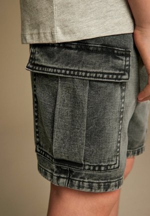 Des shorts cargo en denim gris avec de multiples poches, une coupe décontractée et des coutures visibles. La texture est légèrement usée avec une apparence robuste.