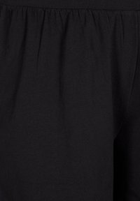 Zwart stof met een zachte, gladde textuur; heeft gathered details in de tailleband, wat een ontspannen pasvorm creëert. Geen patronen of accenten zichtbaar.