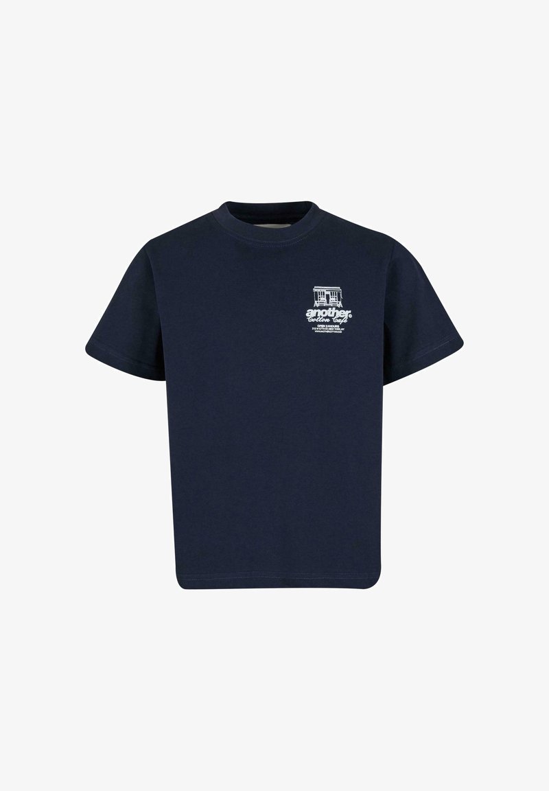 Camiseta de algodón azul marino de manga corta, con cuello redondo y estampado gráfico blanco que presenta un edificio y texto en el área superior izquierda del pecho.