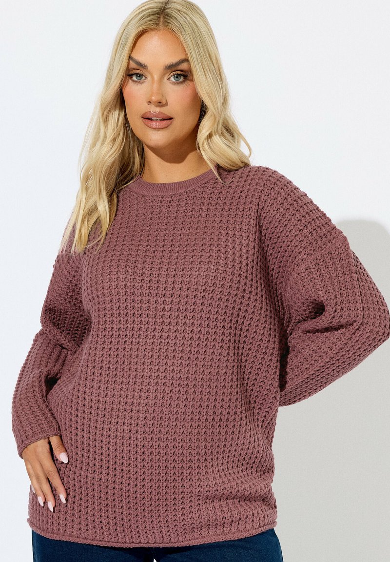 Stickad tröja i mauve, med en texturerad väv, långa ärmar och rund hals. Tyget verkar mjukt och något löst sittande.