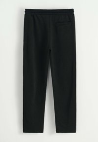 Leggings noirs avec une texture douce, une taille élastique et une poche arrière unique. Présente une coupe slim et un design à jambe droite.