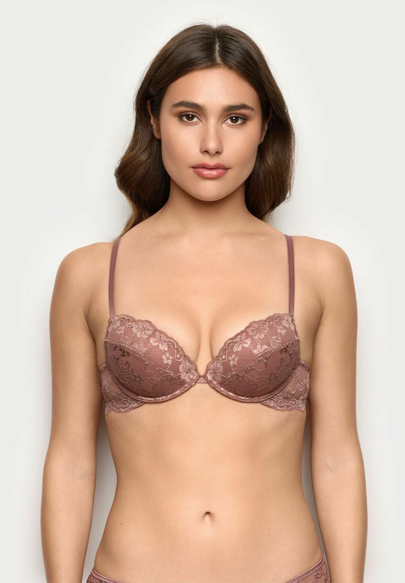 Spitzen-Bralette in staubrosa mit gepolsterten, tief ausgeschnittenen Cups. Verfügt über verstellbare Träger und florale Spitzenverzierungen entlang der Ränder.