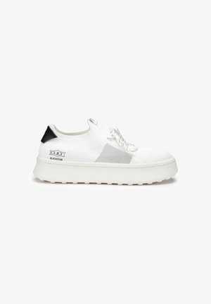 Witte lage sneaker met gebreide stof, zwart hielstuk, grijze zijkantdetail, dikke zool en veters, met het merk "CULT BLACKSTAR" op de zijkant.