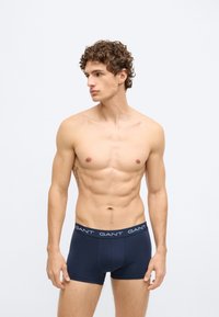 Moške modre bokserice, bombažna mešanica, prilegajoč se dizajn z belim pasom z logotipom; gladka tekstura in strukturirana oblika.