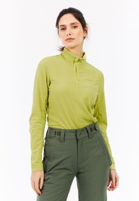 Langærmet pullover i lysegrøn fleece med h�øj krave og halv lynlås. Kombineret med mørkegrønne bukser med lommer.