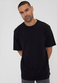 Sort bomulds t-shirt med korte ærmer og rund halsudskæring. Stoffet er glat med en afslappet pasform. Ingen synlige mønstre eller accenter.