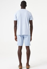 Camiseta de manga corta azul claro combinada con pantalones cortos azul claro a juego. La camiseta tiene un cuello redondo, los pantalones cortos tienen dobladillos enrollados y un ajuste relajado.