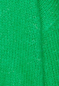 Stickad tyg i klargrön, med en texturerad väv som har synliga fibrer, vilket ger ett mjukt och varmt utseende.