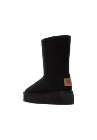 Bottines noires en daim doux, avec un bout rond, une semelle plate et un écusson en cuir brun sur le côté.