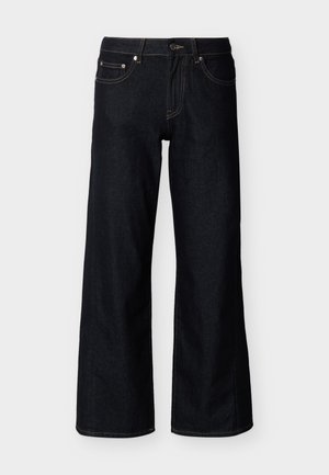 Σκούρο μπλε τζιν παντελόνι με φαρδύ πόδι, με κουμπιά μπροστά, φερμουάρ και πεντατσεπάκι σε απλό ανοιχτό φόντο.