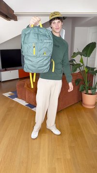 Πράσινο σακίδιο με κίτρινες λεπτομέρειες, με πολλές κλειστές θήκες και υφή στην επιφάνειά του. Φοράει ένα άτομο με πράσινη μπλούζα και κρεμ παντελόνι.