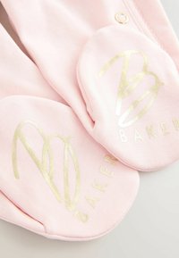 Roosa puuvillane sokk, millel on kuldne logo, millel on tähed "B" ja "Baker." Siledat tekstuuri ja ümarad servad, mis esitlevad brändi detaile.