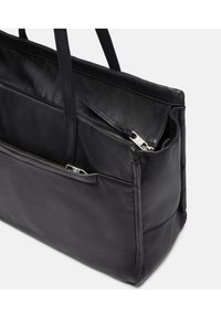 Czarna skórzana torba na ramię z dwiema zamykanymi kieszeniami, długimi paskami, gładką fakturą i prostymi liniami. Oferuje otwartą górną część dla łatwego dostępu.