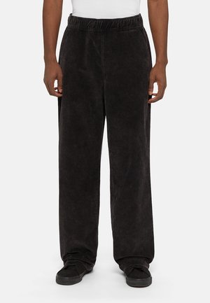 Zwarte, wijde broek van zacht materiaal met een elastische tailleband, voorzien van een platte voorkant en zijzakken. Geen zichtbare logo's.