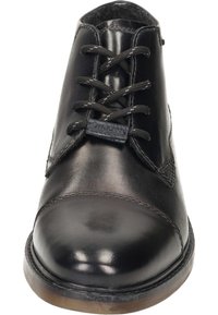 Scarpa in pelle nera con punta arrotondata, design con lacci e dettagli a contrasto. Presenta una suola piatta in gomma e bordi cuciti.