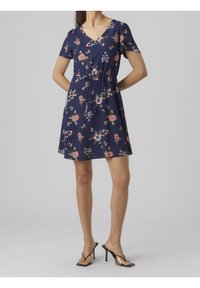 Robe florale marine avec un décolleté en V, des manches courtes et une taille élastique. Présente des fleurs colorées dans des teintes de rose et de vert sur un tissu léger.